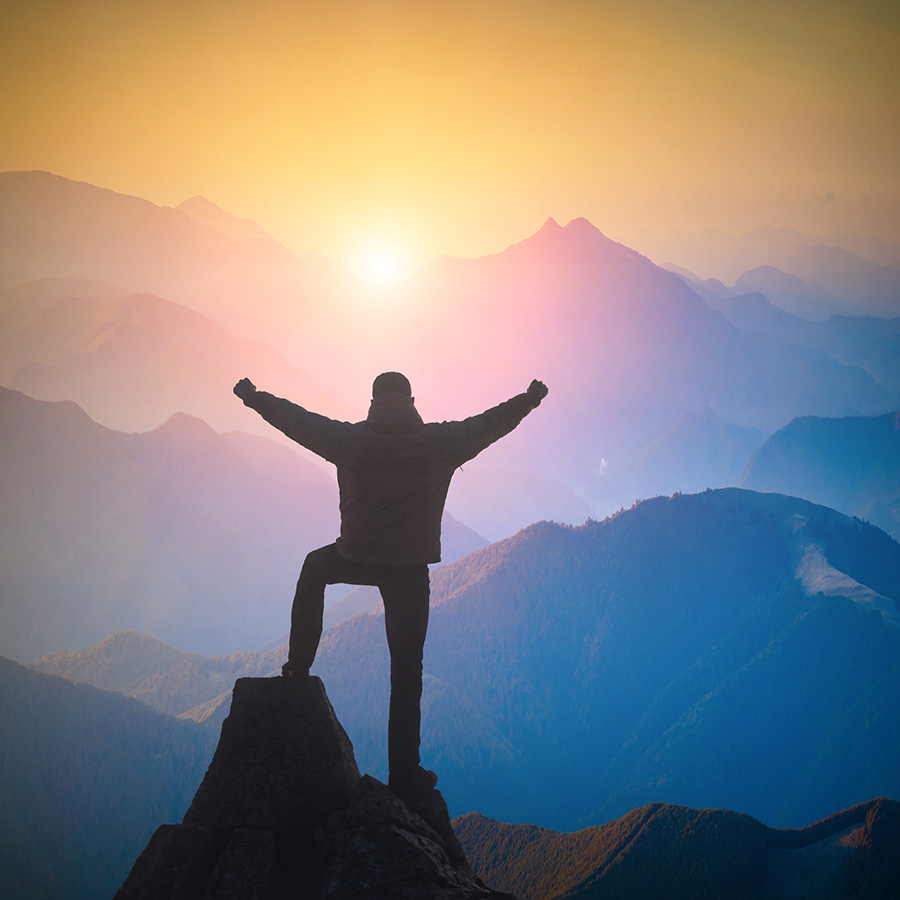 Hiker standing on a cliffs edge and rejoices sunrise